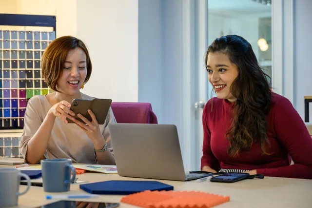 Two women collaborating at a table with a laptop.