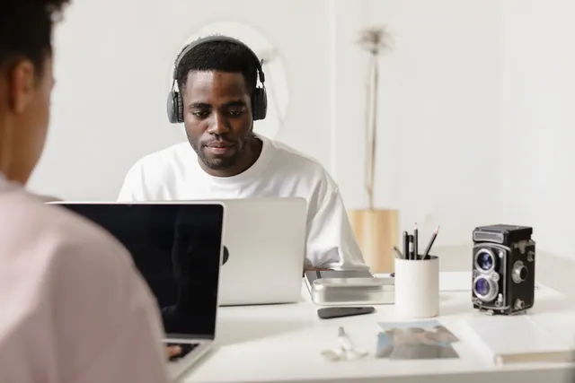 Man concentrating on a laptop in a light workspace.