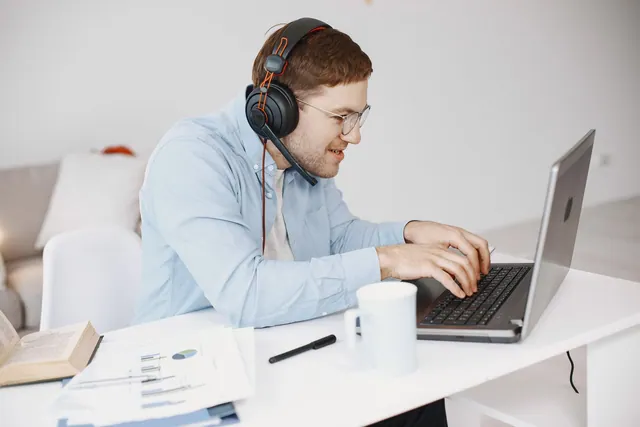 Man wearing headphones while working at his laptop.
