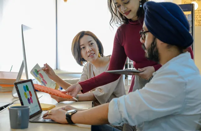 Three people discussing a project around a laptop.