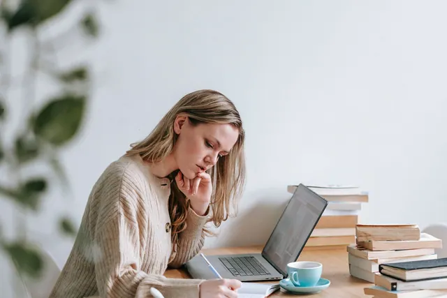 Woman organising her notes beside a laptop.